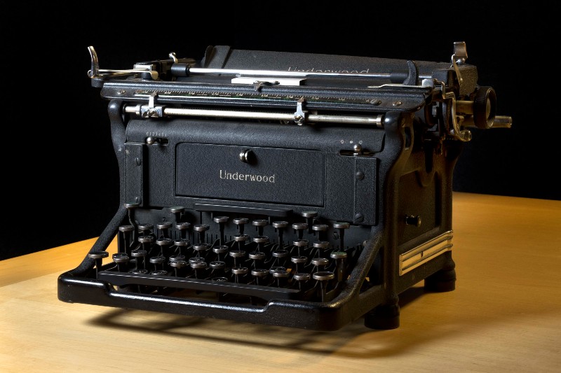 underwood brand black typewriter sitting on a wooden table